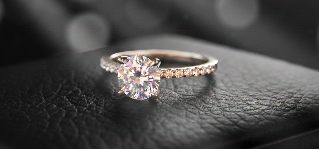 Elegant Black Friday 2025 promotional image from DJP Jewelers & Luxury Buyers. A luxurious white gold diamond ring with a rose-gold band sits prominently on a sleek black leather surface. Rays of light illuminate the vividly colorful ring against a sophisticated black and white background with subtle bokeh, highlighting the exquisite jewelry we buy and sell, including diamonds, gold, watches, and precious metals.