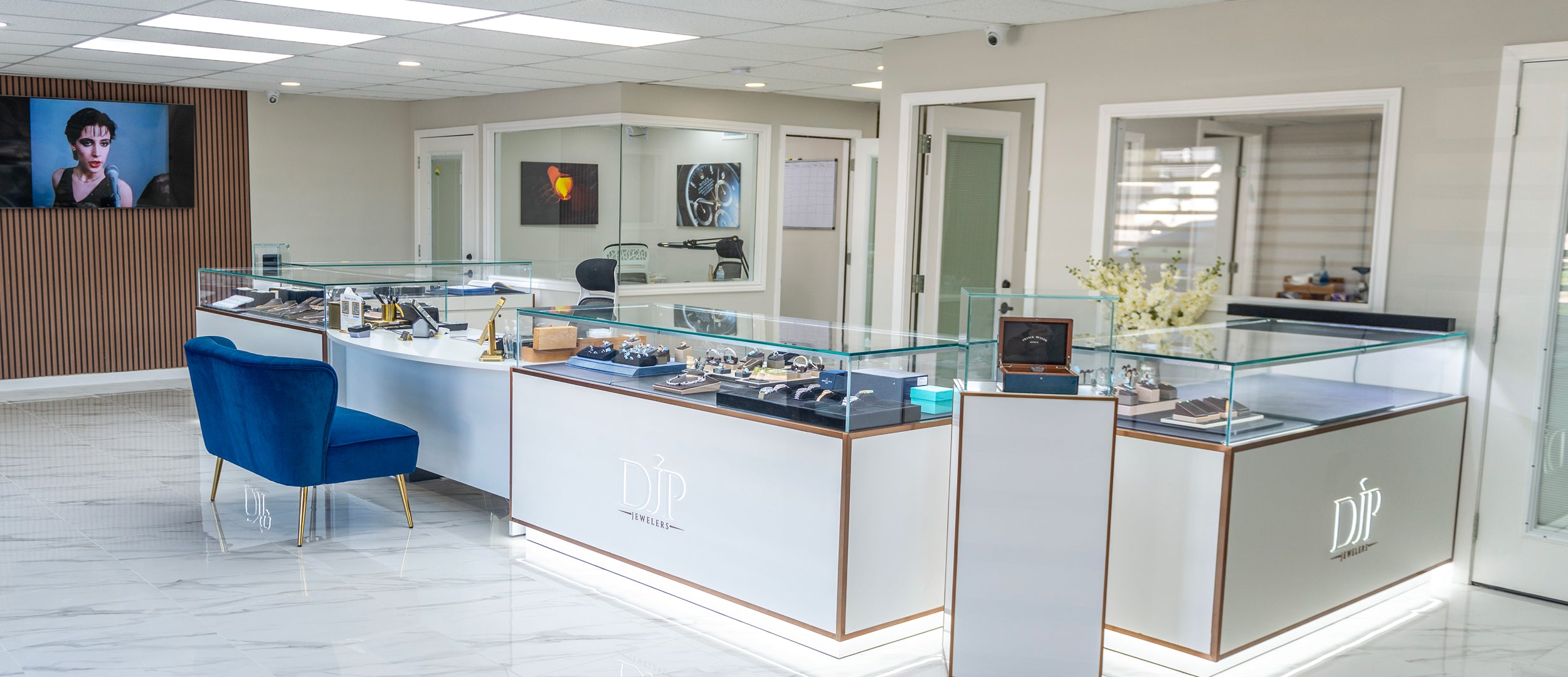 DJP Jewelers & Luxury Buyers - The woodlands/ Spring Location - Luxury marketplace for buying & selling jewelry, diamonds, precious metals and bullion. Modern jewelry store interior with glass display cases and blue chair