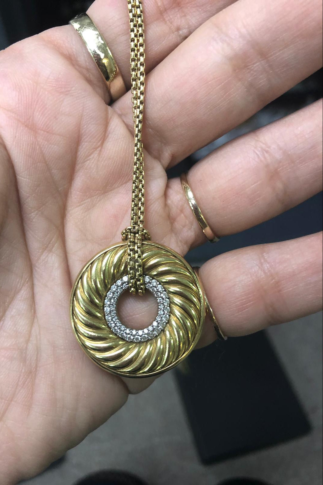 Gold necklace with a circular pendant held in a hand of DJP Buyer - a Gold Jewelry purchased at DJP Jewelers & Luxury Buyers in Sugar Land, TX
