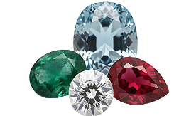 Four gemstones including a green emerald, blue aquamarine, clear diamond, and red ruby on a white background.
